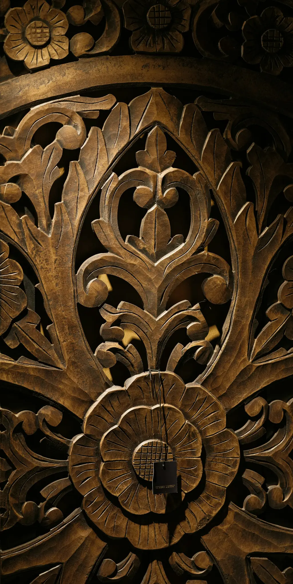 3D floral relief carving on a dark wooden panel