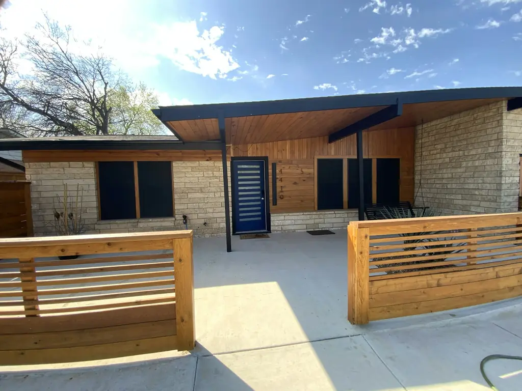 Modern wooden slat gate and fence in front of a house