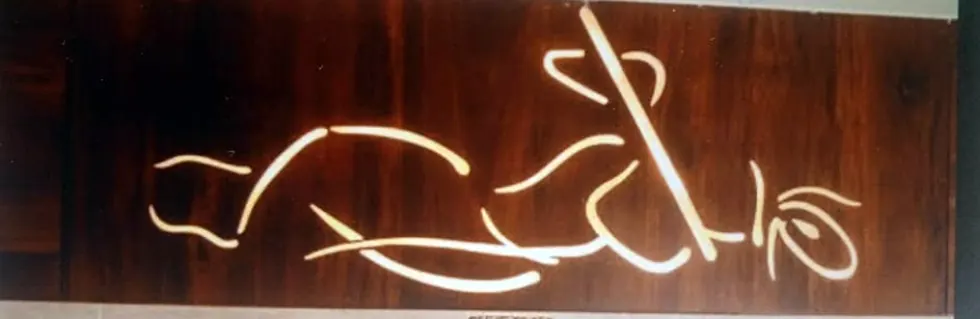 Krishna with flute design engraved on a dark wooden panel